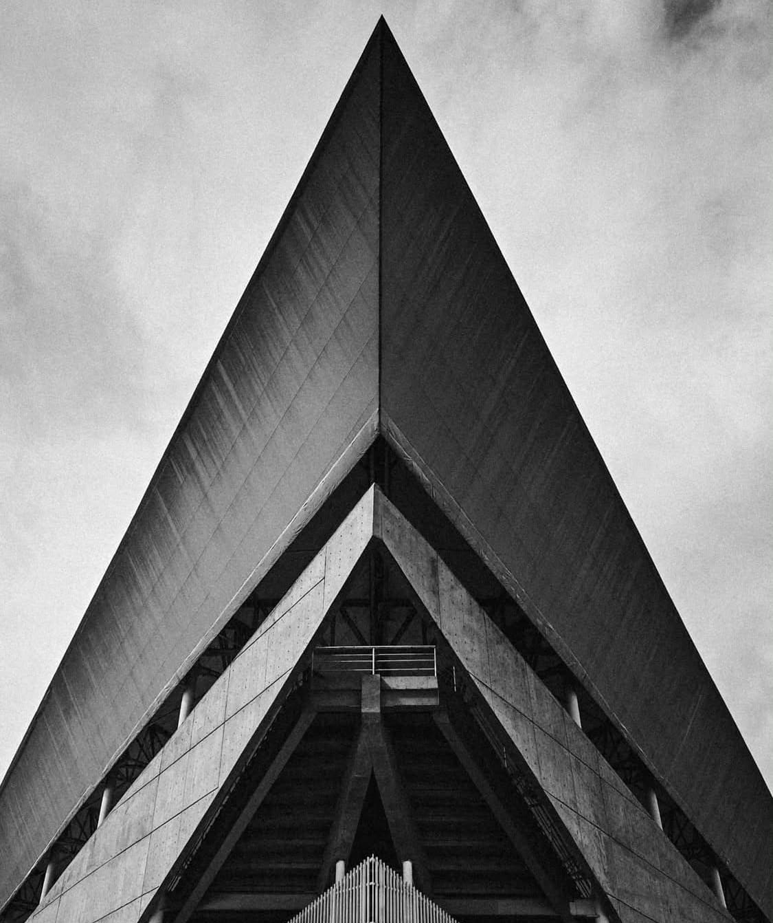 Fachada triangular de concreto vista en contrapicado, en blanco y negro